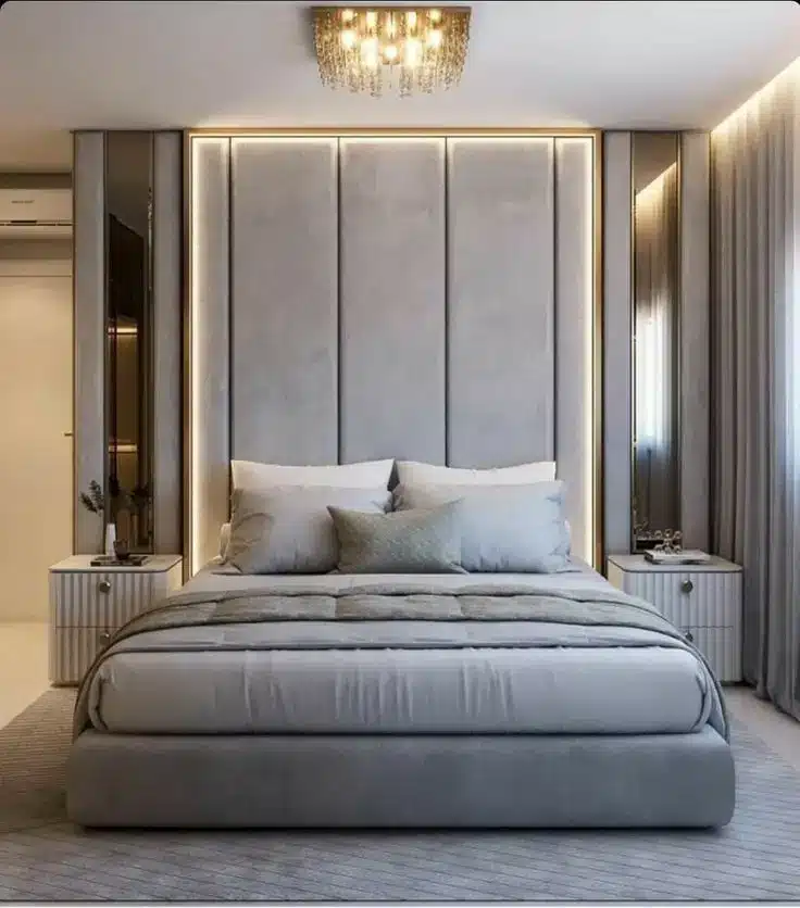 Luxury bedroom with a gray upholstered bed, LED-lit headboard, and modern bedside tables, ideal for homes in Delhi, Gurgaon, and Noida.